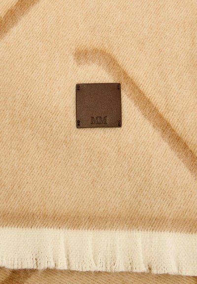 Coperta in lana marrone chiaro con motivo a spina di pesce, con etichetta in pelle marrone scuro con iniziali impresse a rilievo e bordo con frange color crema.