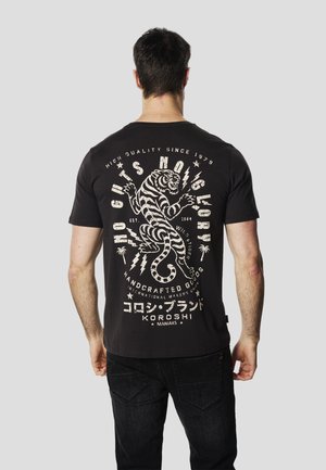 Camiseta negra de manga corta con un gráfico de un tigre blanco en la espalda, acompañado de texto y rayos. Material de algodón, ajuste casual.