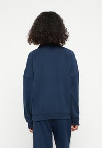 Marineblauwe sweatshirt met een relaxte fit, lange mouwen, ribgebreide boorden en onderrand, zachte textuur, en geen zichtbare merktekens of patronen.