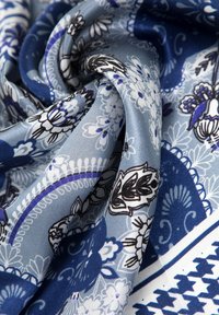 Zijden sjaal met een blauw en grijs bloemenpatroon met zwarte accenten. De stof heeft een gladde textuur en valt soepel.