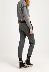 Grå kort sweatshirt med texturerad yta och svart rand, i kombination med mörkgrå smalnar joggers och ankelboots med kontrasterande klack.