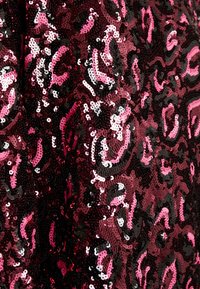 Tissu pailleté en bordeaux et noir avec un motif léopard rose. Présente des sequins ronds brillants, créant une surface texturée et réfléchissante.