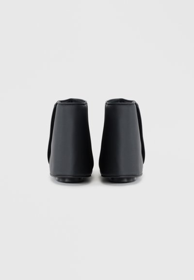Cizme negre până la gleznă, confecționate din piele netedă, cu un design elegant și toc rotund, evidențiate printr-o estetică minimalistă și detalii de coasere gri.