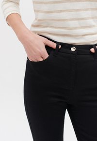 Jeans neri a slim fit, con un classico design a cinque tasche, chiusura con bottone metallico e dettagli di cucitura sottili.