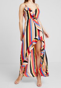 Maksimekko, jossa on raidoitettu helma, sisältäen monivärisiä pystysuoria raitoja punaisena, sinisenä, keltaisena, mustana ja beigenä. V-kaula-aukko, kerroksellinen rakenne.