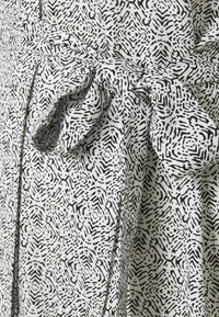 Tissu à motif abstrait noir et blanc noué en un nœud décoratif en forme de boucle.