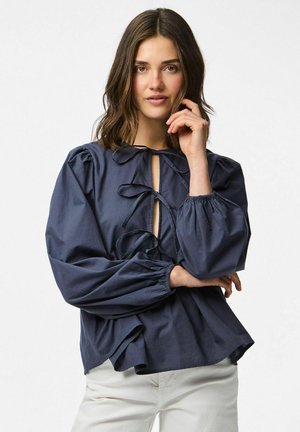 Blusa blu navy con maniche a sbuffo, chiusura davanti a cravatta e profondo scollo a forma di chiave. Realizzata in tessuto leggero, presenta una vestibilità comoda.