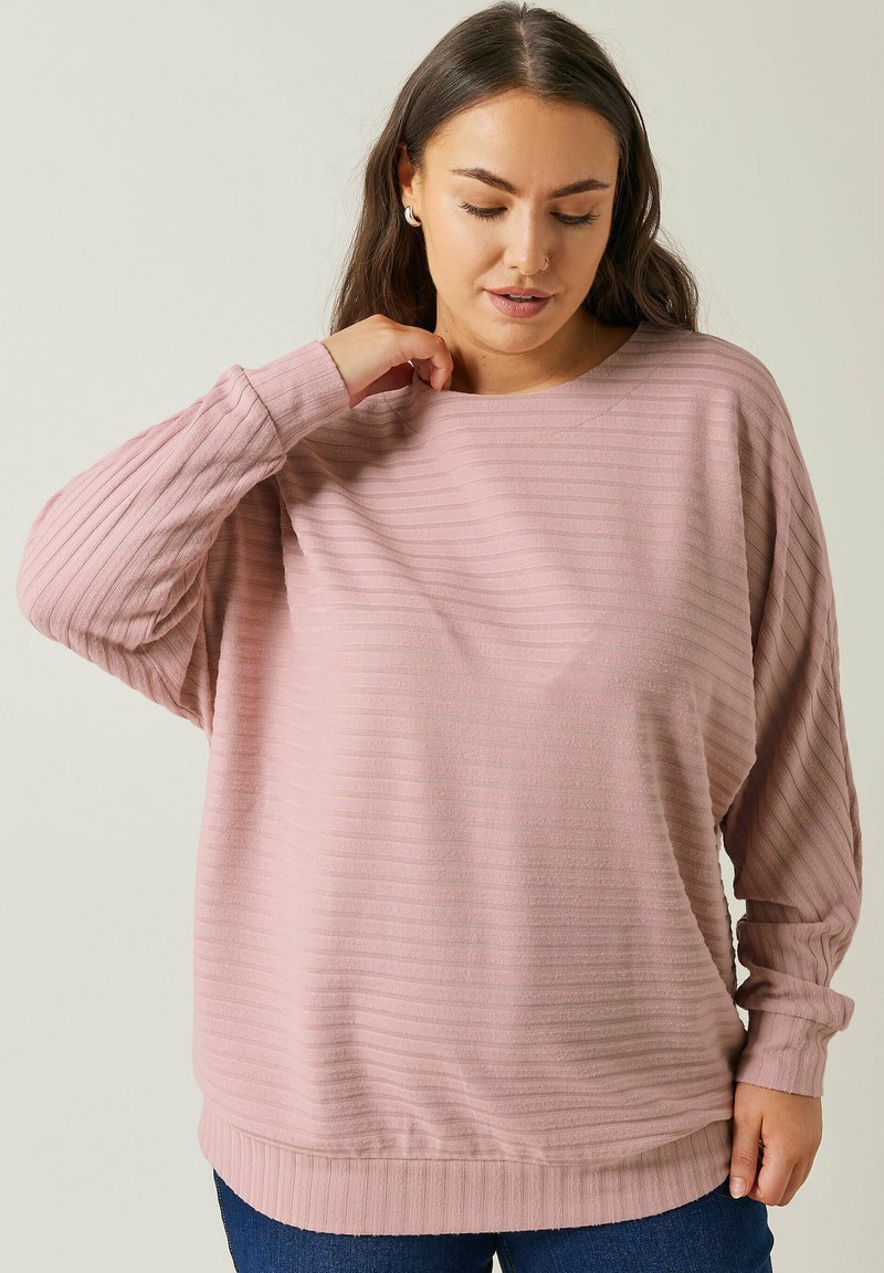 Felpa a maniche lunghe rosa, a coste, con una vestibilità leggermente over size e collo rotondo. Tessuto morbido; orlo inferiore e polsini con banda.