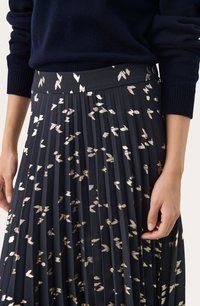 Jupe plissée en tissu bleu marine foncé ornée de motifs en feuille d'or métallisée. Texture lisse, taille élastique, détail de la taille à l'ourlet visible.