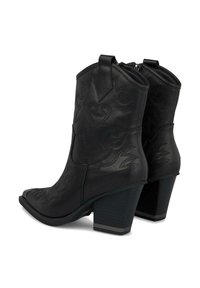Botas de vaquero de cuero negro con punteras puntiagudas, patrones de costura en espiral, cierre de cremallera y tacones gruesos. Superficie texturizada con un acabado mate.