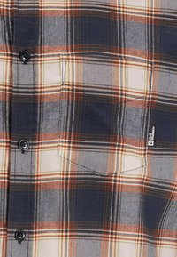 Camicia a quadri con colori blu navy, arancione e beige; chiusura con bottoni nella parte anteriore; taschino sul petto; tessuto morbido con texture e cuciture visibili.