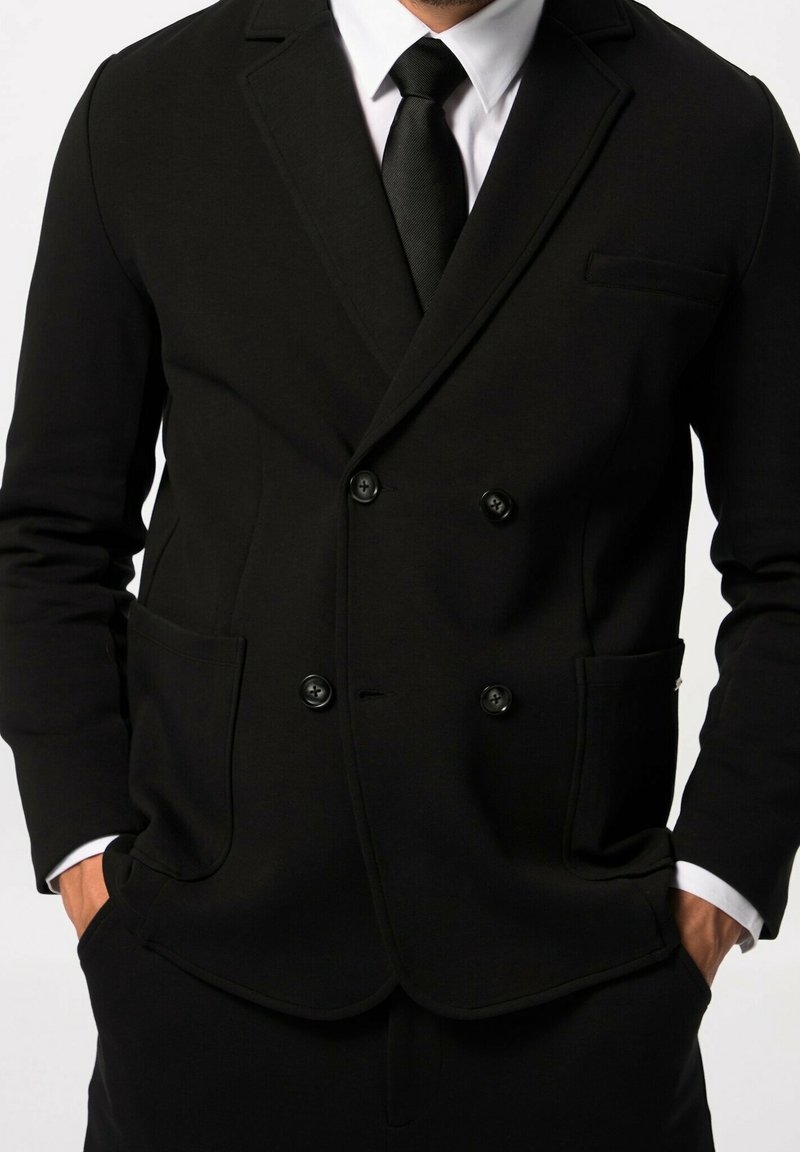 Blazer nero doppiopetto realizzato in tessuto morbido, dotato di due tasche frontali e bottoni neri, con rever a punta e una vestibilità slim.