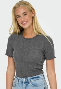 Grå kortærmet top med bølgede kanter, tætsiddende design, lavet af letvægtsstof, parret med lyseblå højtaljede jeans.