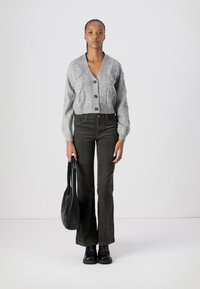 Gray knitted cardigan with a v-neck and five buttons, paired with dark green flared pants. Black flat shoes and a black tote bag.