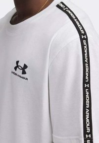 Felpa bianca Under Armour con logo nero sul petto e striscia nera con marchio che scende lungo la spalla e la manica.