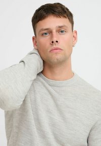 Maglione lavorato a maglia grigio chiaro con scollatura a girocollo e polsini a coste, caratterizzato da una consistenza morbida e da una vestibilità comoda.