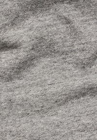 Tela gris con una textura suave, que presenta un sutil patrón jaspeado. Tejido liso y ligero con diferentes tonalidades de gris en toda su extensión.