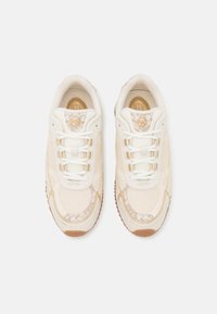 Zapatillas con una parte superior de malla color crema, acentos texturizados y suela de goma color marrón. Cuenta con cordones color crema y un detalle del logo en relieve en la lengüeta.
