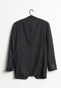 Svart kostymjacka hängande på en krok, med klassisk skärning, slagkrage och knappar på ärmen. Slät tyg med slits bak.