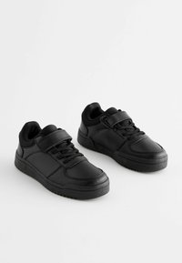 Baskets noires en simili cuir, dotées d'un laçage, d'une sangle Velcro et de semelles en caoutchouc texturé.