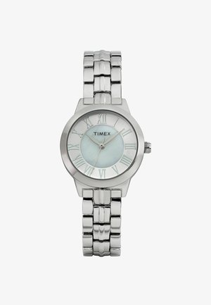 Montre Timex en argent avec un boîtier rond et poli, des chiffres romains, un cadran bleu clair et un bracelet en maillons métalliques.