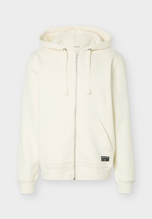 Krēmkrāsas rāvējslēdzēja kapuce ar priekšējiem kabatām, regulējamu auklu kapucē, ribotām aprocēm un mazu melnu zīmola etiķeti uz apakšējās priekšpuses.