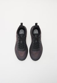 Black athletic shoes with a textured knit upper, featuring a gray accent, traditional lacing system, and a pull tab on the heel.