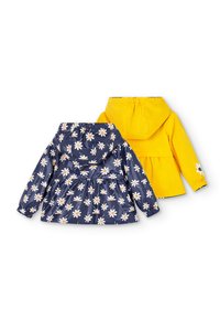 Deux vestes à capuche pour enfants vues de dos, une bleu marine avec des marguerites blanches, une jaune vif unie avec un détail marguerite sur la manche.