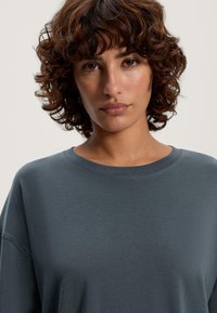 Grå bomulls sweatshirt med rund hals och avslappnad passform, med mjuk textur och minimala sömnadsdetaljer.