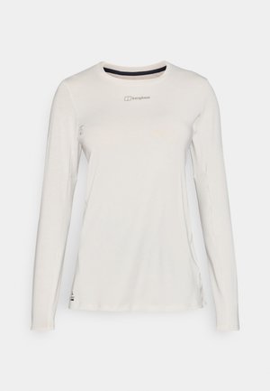 Lange mouw, licht crèmekleurig T-shirt met een ronde hals, zachte textuur, subtiele branding op de borst en zijsplitten voor een gemakkelijke beweging.