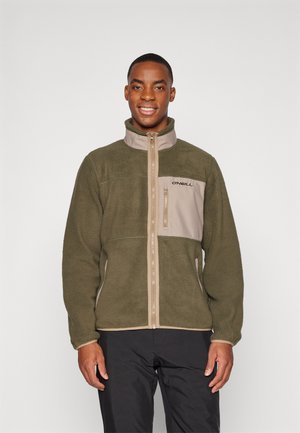 Veste en polaire vert olive avec un panneau avant beige clair et fermeture éclair, dotée d'un col haut et d'un logo sur la poitrine. Tissu texturé.