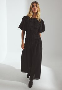 Musthave mustrikk mustri mustbeeri, tekstuurne kangas, riba õlgadel, külgmised lõhikud. Seljas mustad rasteeritud ketsid.