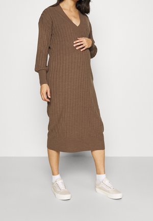 Robe tricotée marron mi-longue avec un décolleté en V et une texture côtelée. Présente des manches longues et une coupe décontractée, associée à des baskets légères.