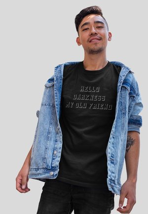 Sort t-shirt med præget skrift "HELLO DARKNESS MY OLD FRIEND," båret under en lyseblå denimjakke med knapper og en afslappet pasform.
