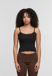 Black ribbed tank top with thin straps, fitted design, and rounded neckline, paired with brown high-waisted leggings. Smooth texture.
