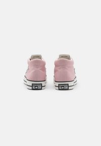 Pink canvas high-top sneakers with white rubber soles, featuring black accents, logo on the heel, and classic lace-up design.