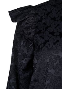 Zwarte stof met een verhoogd bloemmotief in jacquard en korte pofmouwen.