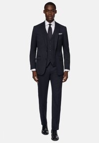Marinblå tre-dels kostym med väst, skräddarsydd passform, tillverkad av slät tyg. Inkluderar en vit skjorta, mörk slips och svarta putsade skor.