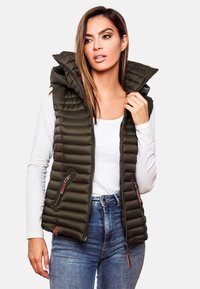 Doudoune olive avec un col haut et des poches zippées, présentant un design matelassé. Portée sur un haut blanc et associée à un jean.