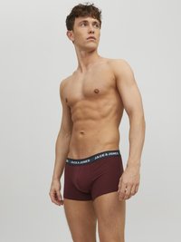Burgunderfarbene Boxershorts mit einem schwarzen Bund, der den Text "JACK & JONES" trägt. Der Stoff wirkt weich und dehnbar und ergänzt ein angepasstes Design.
