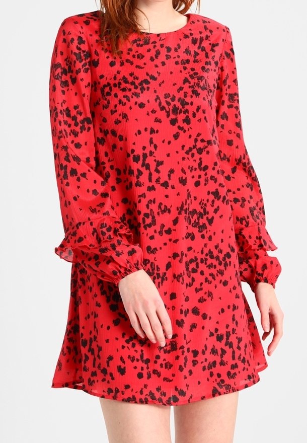 Rotes Kleid mit schwarzen Sprenkeln, runder Ausschnitt und langen Ärmeln mit Rüschensäumen. Leichter, fließender Stoff mit strukturierter Optik.