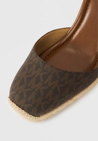 Καφέ παπούτσι πλατφόρμα με σχέδι ο, με υφασμάτινη συνθετική επάνω επιφάνεια, εσωτερική επένδυση από λείο δέρμα και σόλα τυλιγμένη με τζούτ. Σχεδιασμός με τετράγωνη μύτη.