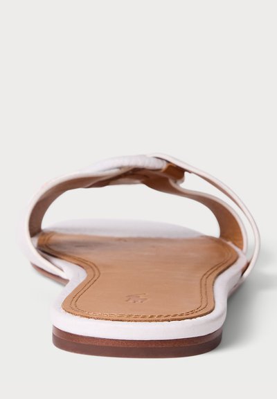 Sandalha plana branca com sola de couro, apresentando uma tira larga e uma forma levemente curvada. Textura suave e design minimalista com pormenores em castanho.