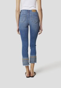 Spijkerbroeken met een middelhoog model, lichtblauwe wassing, geborduurde rand aan de zoom en een leren merklabel op de tailleband.