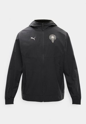 Černá puma bunda s kapucí, předním zipem, elastickými manžetami, bočními kapsami a bílým emblémem na levé straně hrudi.