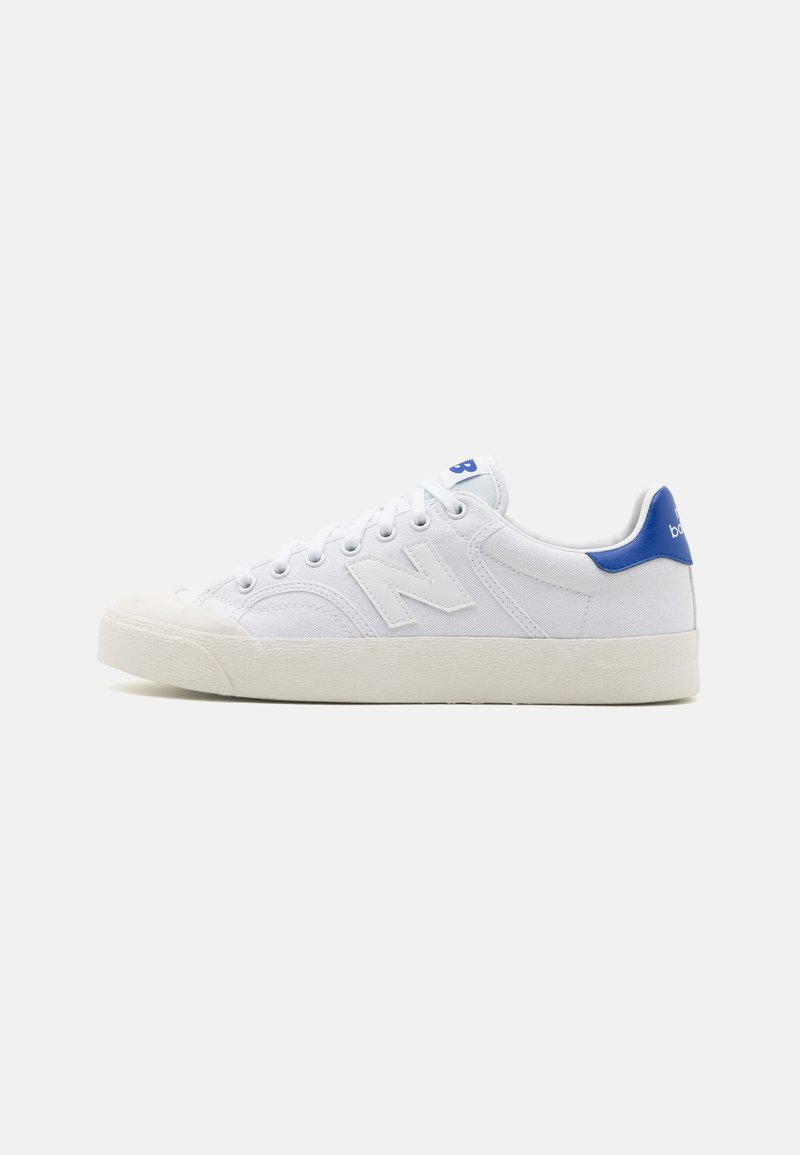 Tenis de lona brancos com bico arredondado, apresentando realces azuis no calcanhar e um grande logótipo branco "N" na lateral. Sola de borracha texturizada.