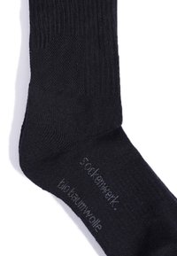 Schwarze Baumwollsocken mit geripptem Muster, versehen mit bedrucktem Text an der Seite. Material als Bio-Baumwolle gekennzeichnet. Einfaches Design.