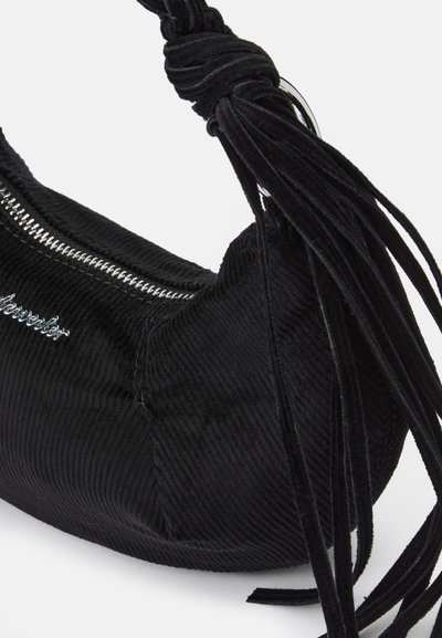 Svart kordflorväska med rundad form. Den har ett silverfärgat blixtlås och ett knutet handtag med texturerade fransdetaljer.