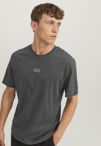 Czarny bawełniany t-shirt z krótkim rękawem, okrągłym dekoltem i subtelnym nadrukiem logo "JACK & JONES" na piersi. Gładka tekstura.