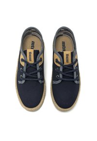 Zapatos de lona azul marino con acentos beiges, punta redonda y entresuela de yute trenzado. Presenta cordones oscuros y un pequeño logotipo en la plantilla.